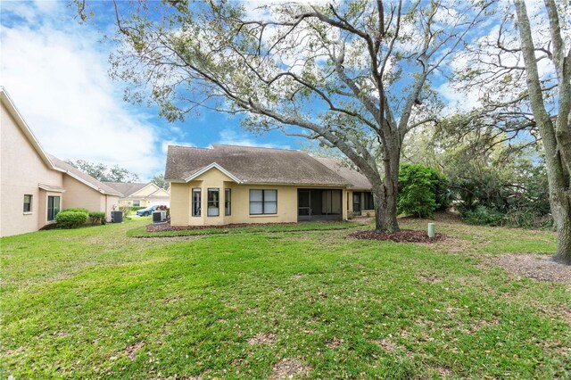 back of house with central AC unit and a yard