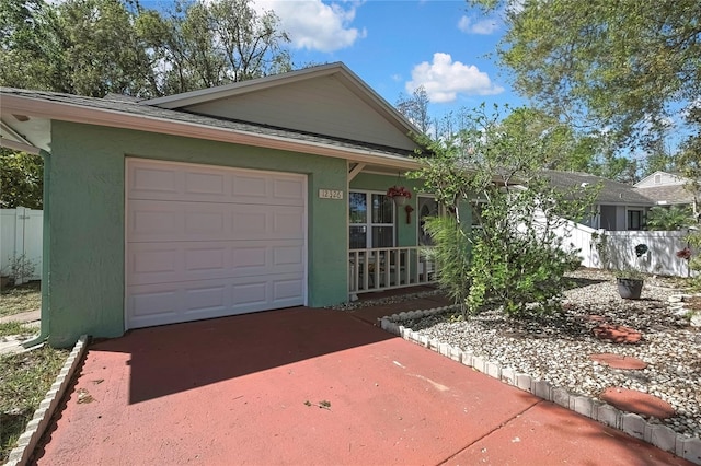 ranch-style home featuring fence, driveway, an attached garage, and stucco siding