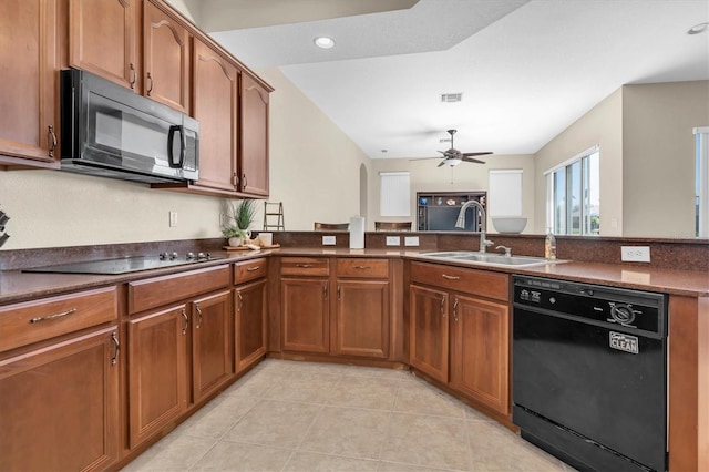 kitchen with brown cabinetry, a ceiling fan, a sink, black appliances, and dark countertops