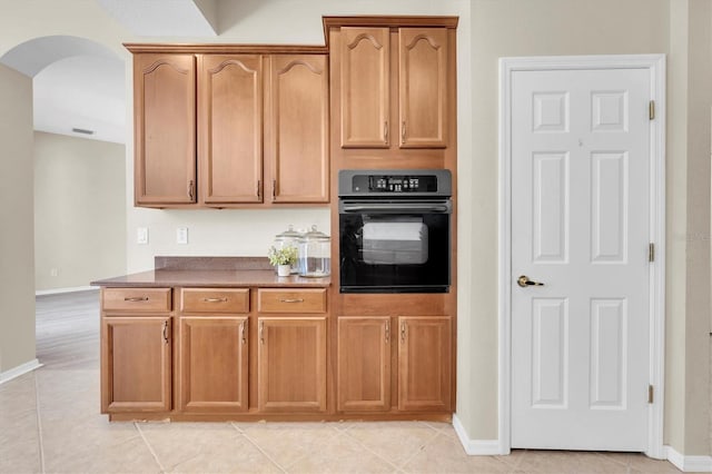 kitchen with arched walkways, light tile patterned floors, oven, and visible vents