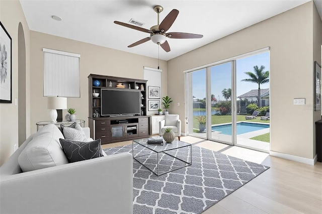 living area with baseboards, wood finished floors, visible vents, and ceiling fan