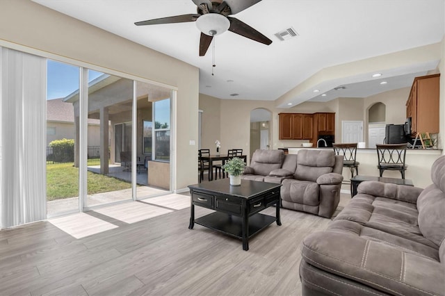 living area with visible vents, ceiling fan, light wood-style flooring, recessed lighting, and arched walkways