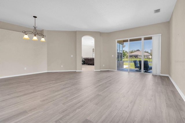 unfurnished room featuring visible vents, arched walkways, baseboards, and light wood-style flooring