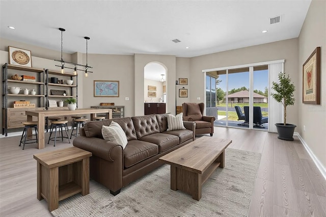 living area with visible vents, light wood-style flooring, recessed lighting, arched walkways, and baseboards