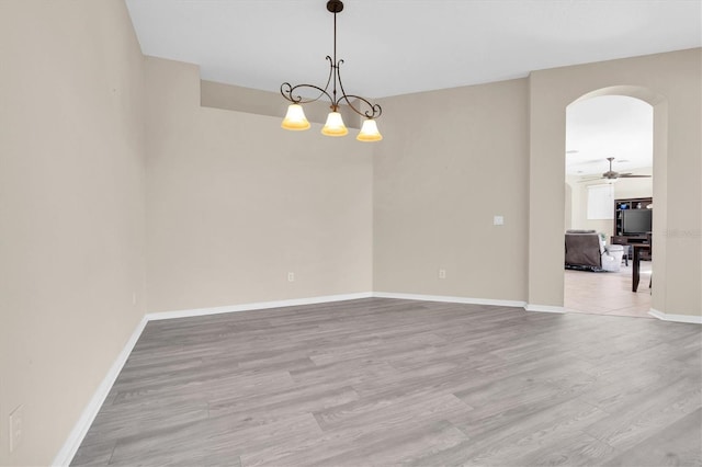 unfurnished room featuring light wood-style flooring, baseboards, arched walkways, and ceiling fan