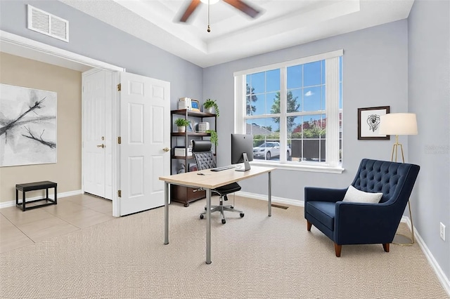 carpeted office featuring a tray ceiling, baseboards, and visible vents