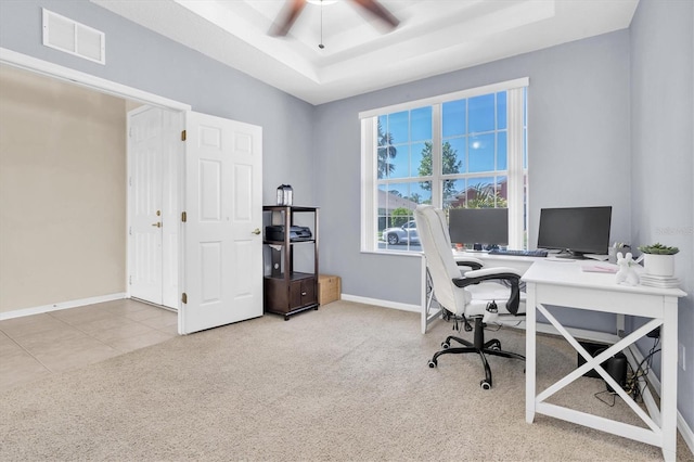 carpeted home office with a ceiling fan, baseboards, visible vents, a raised ceiling, and tile patterned floors