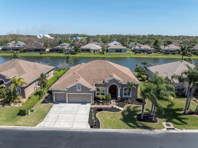 view of front facade with a garage, a residential view, driveway, and a water view