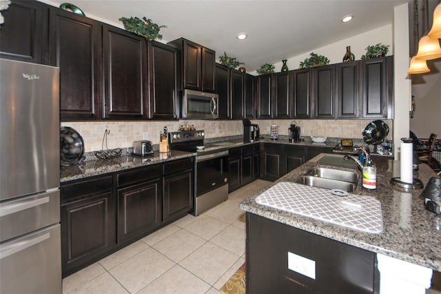 kitchen with backsplash, appliances with stainless steel finishes, stone countertops, light tile patterned flooring, and a sink