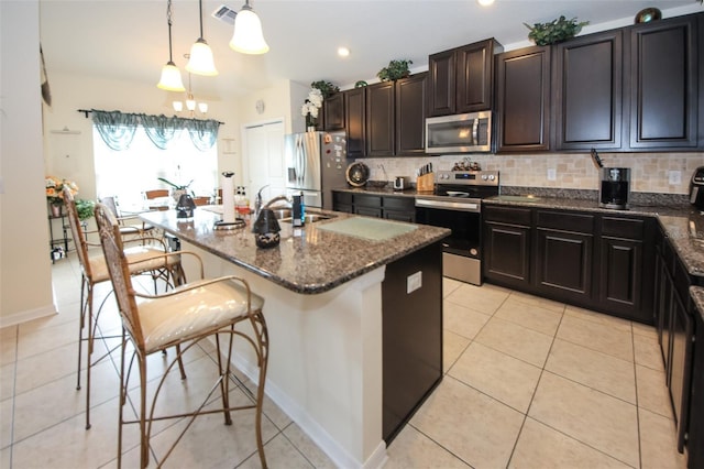 kitchen featuring a breakfast bar area, a kitchen island with sink, visible vents, appliances with stainless steel finishes, and decorative backsplash