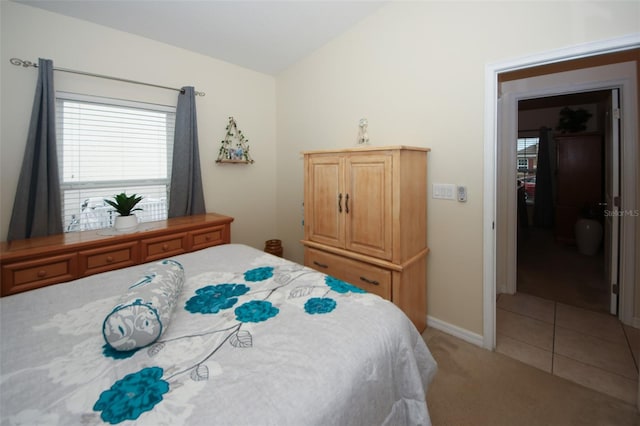 bedroom featuring lofted ceiling, light carpet, and light tile patterned flooring