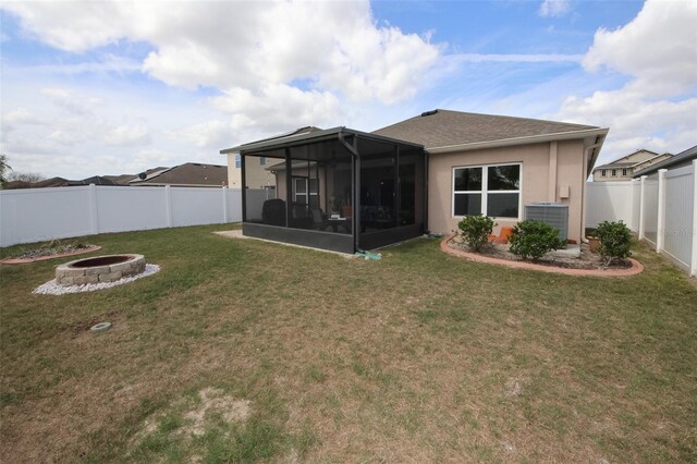 rear view of property featuring an outdoor fire pit, a fenced backyard, a sunroom, a lawn, and stucco siding