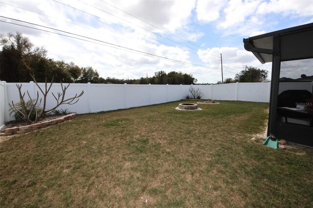 view of yard featuring a fenced backyard and a fire pit