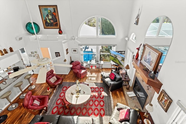 living room with a towering ceiling, a ceiling fan, and wood finished floors