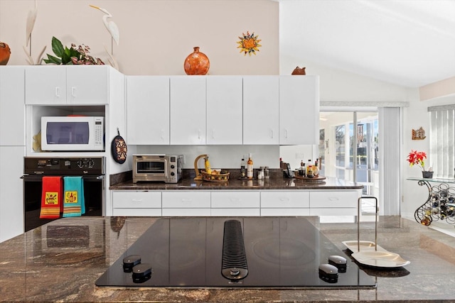 kitchen featuring a toaster, white cabinetry, vaulted ceiling, dark stone countertops, and black appliances