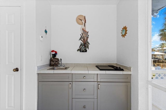 bar with black stovetop and a sink