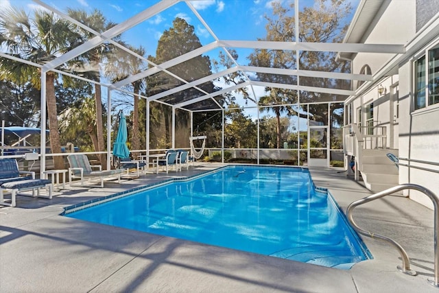 view of swimming pool featuring glass enclosure, a fenced in pool, and a patio