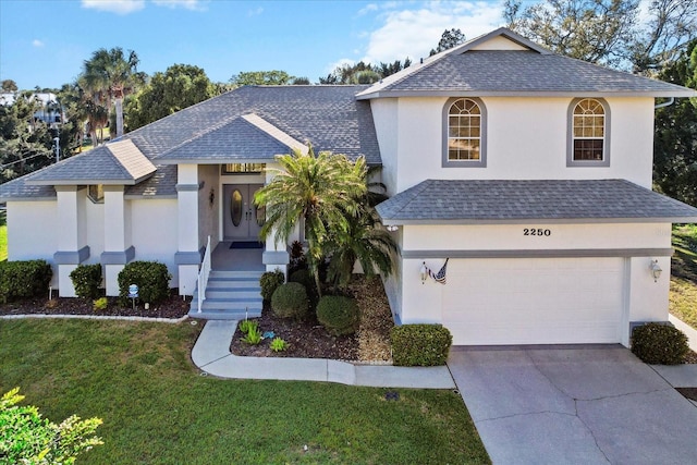 view of front facade featuring driveway, roof with shingles, a front yard, and stucco siding