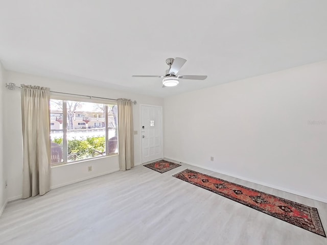 empty room featuring light wood-style flooring, baseboards, and a ceiling fan