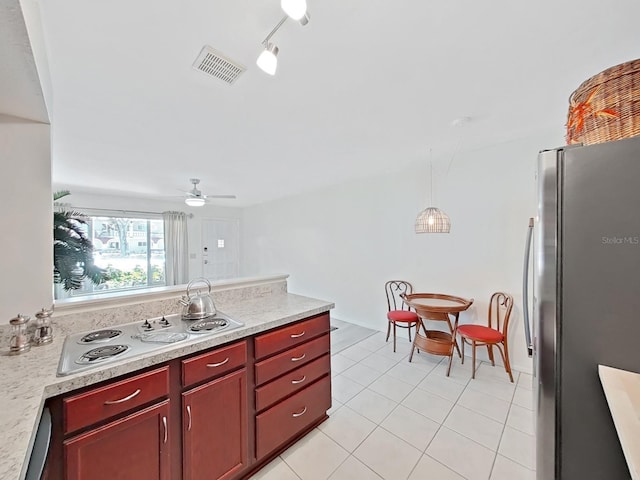 kitchen with electric cooktop, visible vents, light countertops, freestanding refrigerator, and reddish brown cabinets