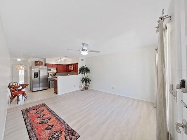 living area with light wood-type flooring, a ceiling fan, and baseboards