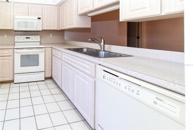 kitchen with light tile patterned floors, light countertops, white appliances, and a sink