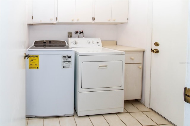 laundry room featuring light tile patterned floors, washing machine and clothes dryer, and cabinet space