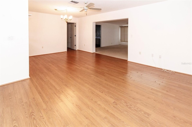 spare room with light wood-type flooring, visible vents, and ceiling fan with notable chandelier