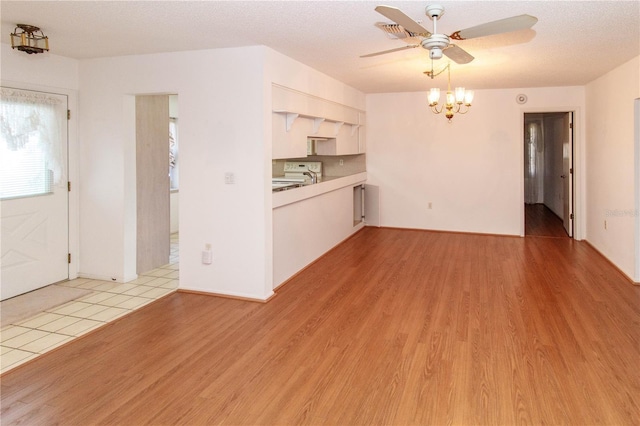 interior space featuring light wood-style floors, visible vents, a textured ceiling, and ceiling fan with notable chandelier