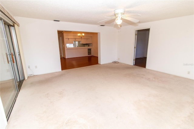 empty room featuring carpet flooring, a textured ceiling, and ceiling fan with notable chandelier