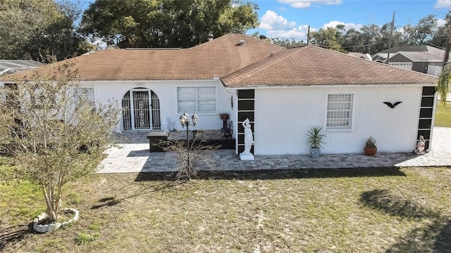 back of property with a patio area, a yard, and stucco siding