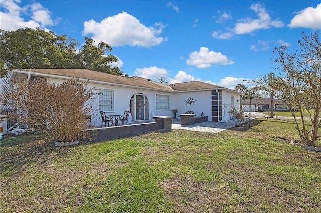 rear view of house featuring a yard, a patio, and stucco siding