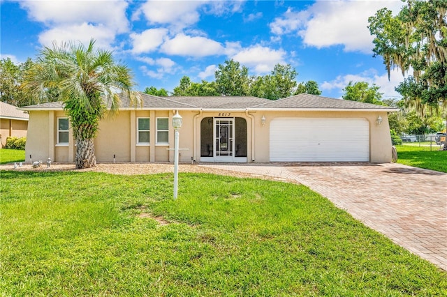 ranch-style home featuring a front yard, decorative driveway, an attached garage, and stucco siding