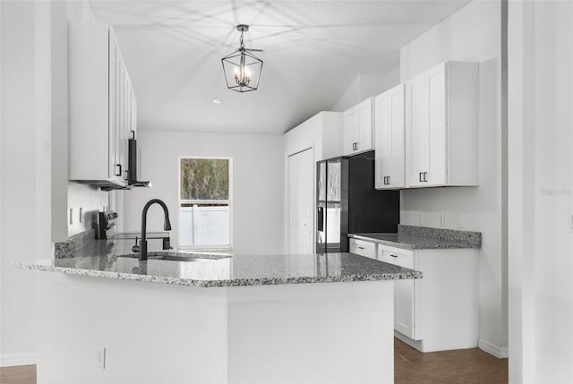kitchen featuring white cabinets, a sink, light stone countertops, a peninsula, and black fridge