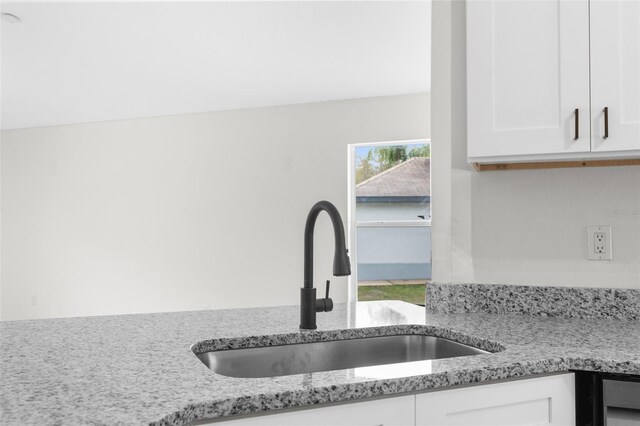 details with light stone counters, white cabinetry, and a sink