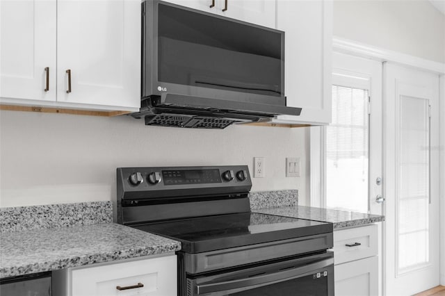 kitchen featuring stainless steel range with electric stovetop, white cabinets, and light stone counters