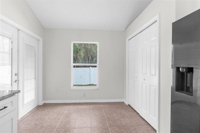 unfurnished bedroom featuring a closet, light tile patterned flooring, and baseboards