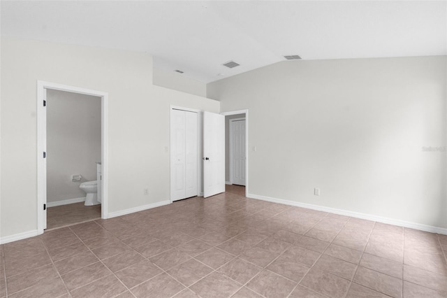 unfurnished bedroom featuring vaulted ceiling, connected bathroom, visible vents, and baseboards