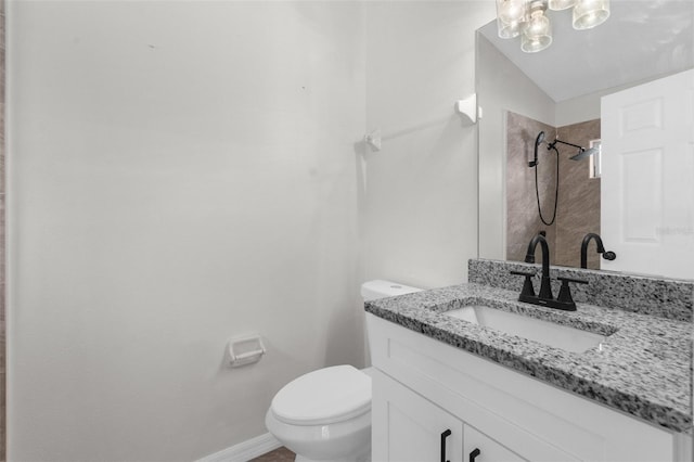 bathroom featuring a shower, vanity, toilet, and baseboards