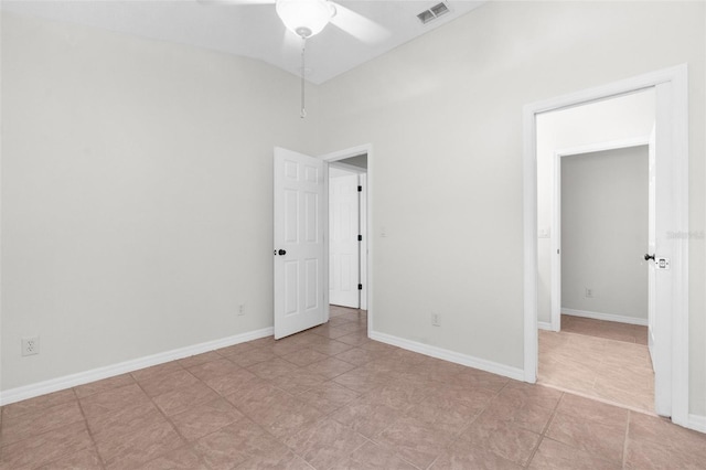 spare room featuring baseboards, visible vents, and vaulted ceiling