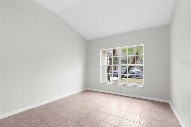 unfurnished room featuring vaulted ceiling, light tile patterned flooring, and baseboards