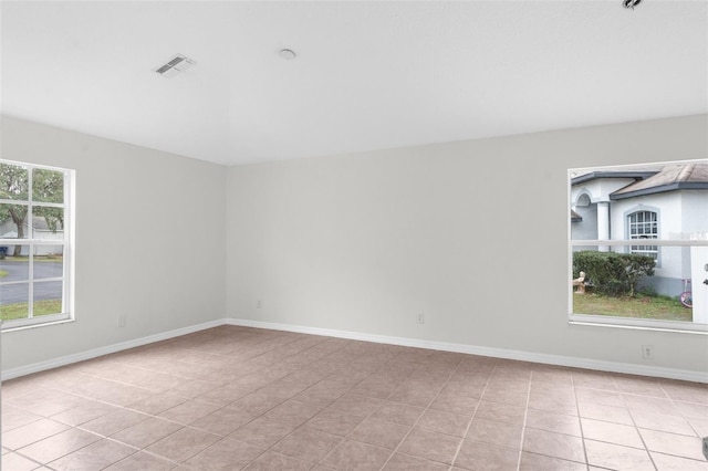 empty room featuring light tile patterned floors, visible vents, and baseboards