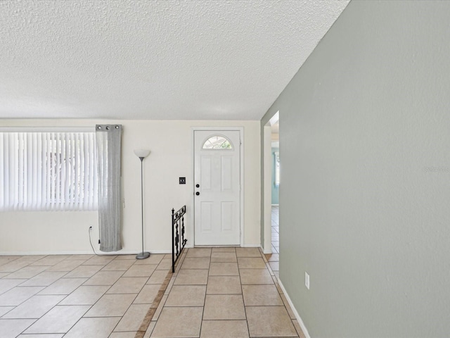 foyer featuring light tile patterned floors, baseboards, and a textured ceiling