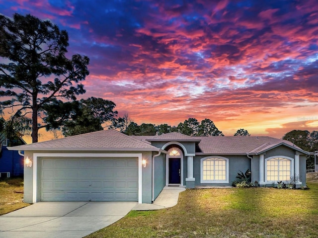 ranch-style house with concrete driveway, a front lawn, an attached garage, and stucco siding