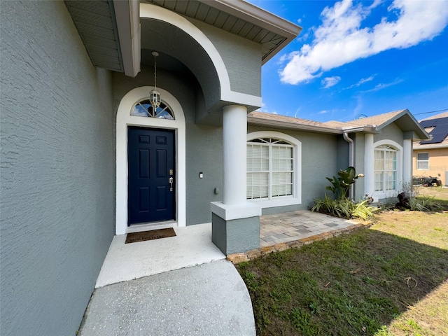 entrance to property featuring a yard and stucco siding