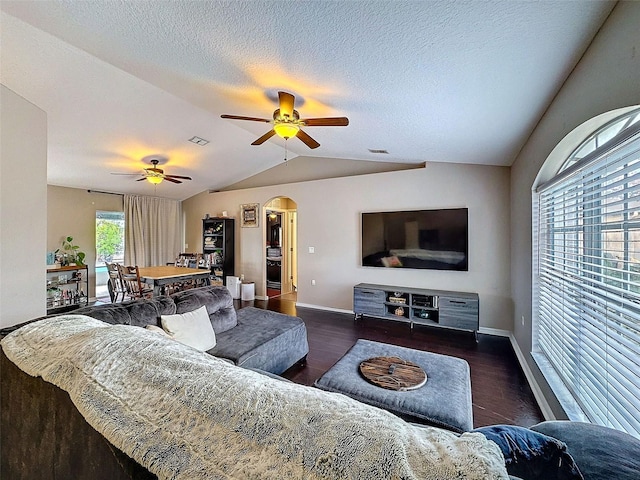 living area with arched walkways, vaulted ceiling, wood finished floors, and baseboards