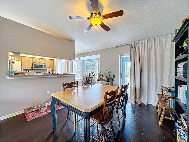 dining area featuring a textured ceiling, dark wood-style flooring, a ceiling fan, baseboards, and vaulted ceiling