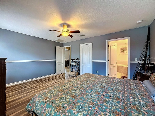 bedroom featuring a ceiling fan, a textured ceiling, visible vents, and wood finished floors