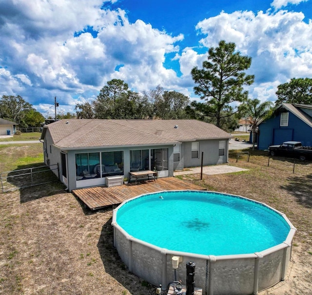 view of swimming pool featuring a sunroom, fence, and a wooden deck