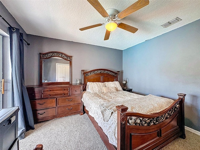 bedroom featuring light carpet, a textured ceiling, visible vents, and a ceiling fan